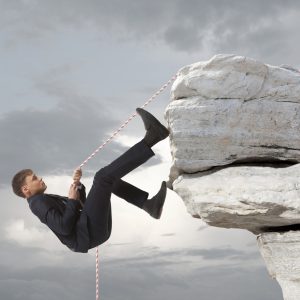 Young businessman scaling a rock Business concept